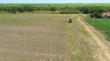 Dolly 'nin üstündeki kamera traktörü takip ediyor. Ta ki bitmeyen tarlaları püskürterek ekili bir tarlaya yayılmış tarımsal püskürtücüleri sürükleyene kadar..
