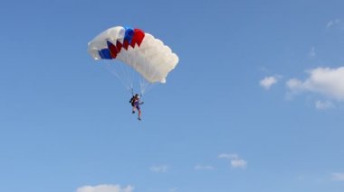 Mavi gökyüzünde paraşüt. Paraşütçü açık bir paraşütle yavaşça iniyor. Hava dalışı, süzülüş, paraşütle atlama
