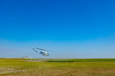 Helikopter yeşil çayırdan havalanıyor ve alçaktan uçuyor..
