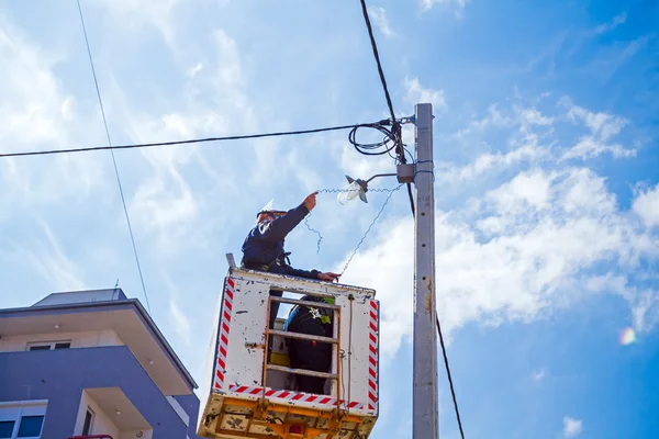 Team di linee elettriche al lavoro su un palo — Foto Stock