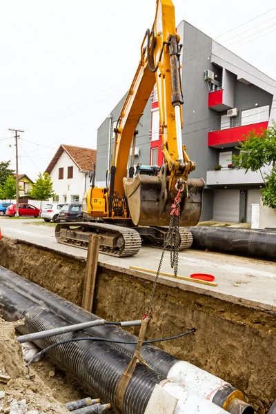 Excavator galben la șantierul de construcții în așezare urbană — Fotografie, imagine de stoc