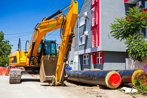 Gelber Bagger auf Baustelle in städtischer Siedlung — Stockfoto