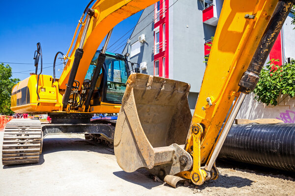 Желтый экскаватор на строительной площадке в городском поселке
 