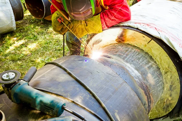 Nära upp skott svetsare till svetsning, gnistor flyger omkring. — Stockfoto