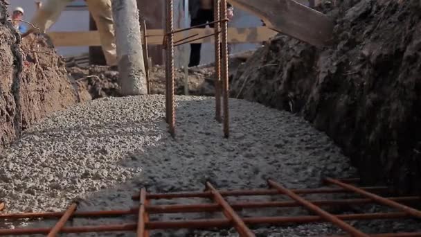 Beton breitet sich im Fundament über Bewehrungsstangen aus. — Stockvideo
