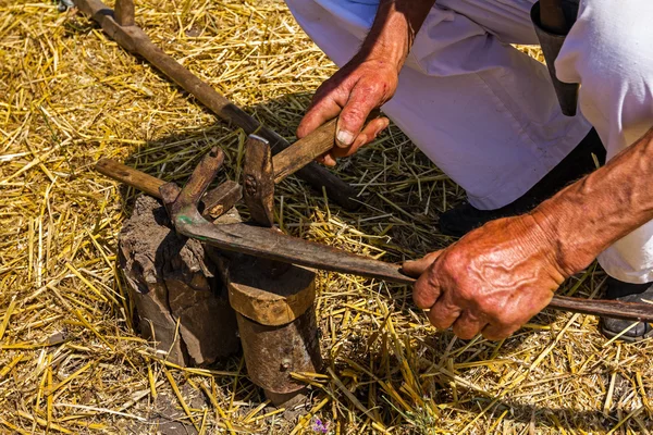 Bauer schärft, bügelt, repariert die Klinge an der Sense. — Stockfoto