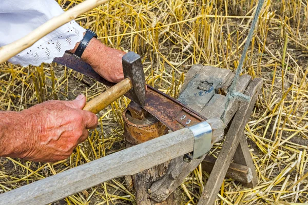 Farmář je ostření, žehlení, opravy ostří na Kosu. — Stock fotografie