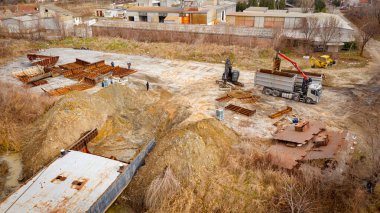 Above view on excavator and tow grapple truck with hydraulic grappling claw, multivalve grab hand, gripper machine, manipulator, loading part of vessel into container, collect rusty metal, recycling.