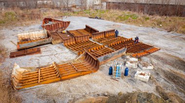 Above view on workers as they cutting parts of old large vessel into smaller pieces, barge, dismantling ship, cut out rusty metal for scarp, using acetylene torch, recycling, sparks are fly around.
