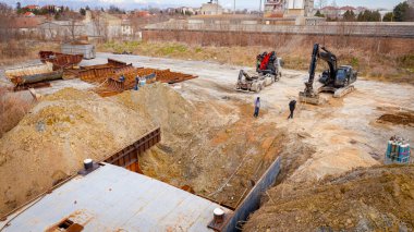 Manzaralı kazıcı ve çekicinin üstünde birlikte eski yük gemisinin yatağının bir kısmını çekiyorlar, mavna, nehir kıyısı, kazma, sökme gemisi, paslı metali kesme, geri dönüşüm....