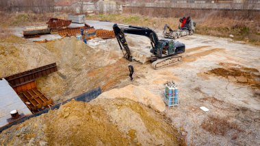 Manzaralı kazıcı ve çekicinin üstünde birlikte eski yük gemisinin yatağının bir kısmını çekiyorlar, mavna, nehir kıyısı, kazma, sökme gemisi, paslı metali kesme, geri dönüşüm....