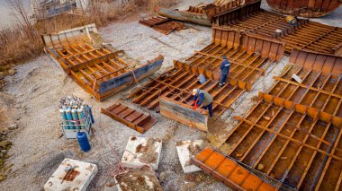 Above view on workers as they cutting parts of old large vessel into smaller pieces, barge, dismantling ship, cut out rusty metal for scarp, using acetylene torch, recycling, sparks are fly around.