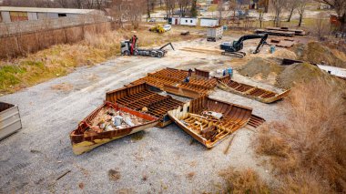 Manzaralı kazıcı ve çekicinin üstünde birlikte eski yük gemisinin yatağının bir kısmını çekiyorlar, mavna, nehir kıyısı, kazma, sökme gemisi, paslı metali kesme, geri dönüşüm....