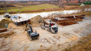 Manzaralı kazıcı ve çekicinin üstünde birlikte eski yük gemisinin yatağının bir kısmını çekiyorlar, mavna, nehir kıyısı, kazma, sökme gemisi, paslı metali kesme, geri dönüşüm....