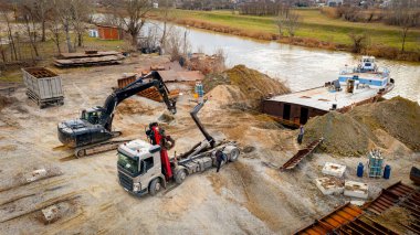 Manzaralı kazıcı ve çekicinin üstünde birlikte eski yük gemisinin yatağının bir kısmını çekiyorlar, mavna, nehir kıyısı, kazma, sökme gemisi, paslı metali kesme, geri dönüşüm....