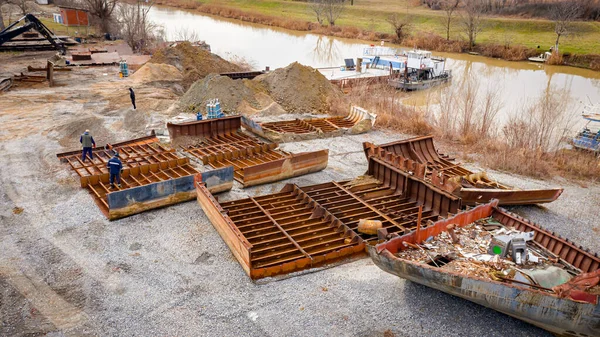 Above view on workers as they cutting parts of old large vessel into smaller pieces, barge, dismantling ship, cut out rusty metal for scarp, using acetylene torch, recycling, sparks are fly around.