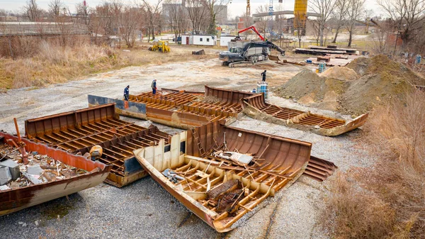 Above view on workers as they cutting parts of old large vessel into smaller pieces, barge, dismantling ship, cut out rusty metal for scarp, using acetylene torch, recycling, sparks are fly around.