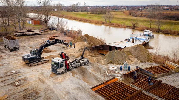 Manzaralı kazıcı ve çekicinin üstünde birlikte eski yük gemisinin yatağının bir kısmını çekiyorlar, mavna, nehir kıyısı, kazma, sökme gemisi, paslı metali kesme, geri dönüşüm....