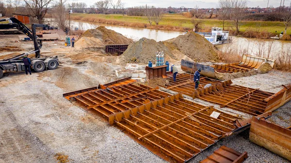 Manzaralı kazıcı ve çekicinin üstünde birlikte eski yük gemisinin yatağının bir kısmını çekiyorlar, mavna, nehir kıyısı, kazma, sökme gemisi, paslı metali kesme, geri dönüşüm....