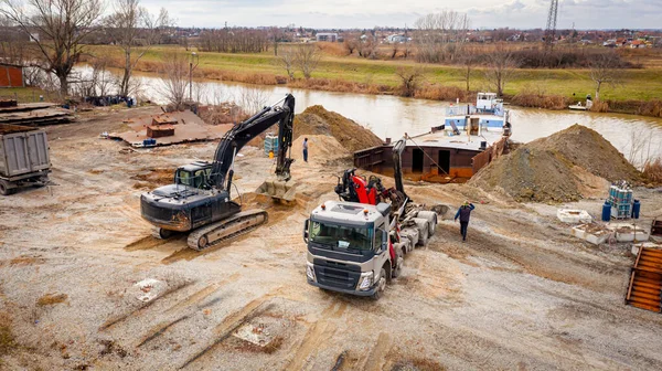 Manzaralı kazıcı ve çekicinin üstünde birlikte eski yük gemisinin yatağının bir kısmını çekiyorlar, mavna, nehir kıyısı, kazma, sökme gemisi, paslı metali kesme, geri dönüşüm....