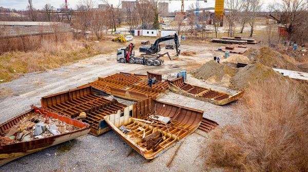 Manzaralı kazıcı ve çekicinin üstünde birlikte eski yük gemisinin yatağının bir kısmını çekiyorlar, mavna, nehir kıyısı, kazma, sökme gemisi, paslı metali kesme, geri dönüşüm....