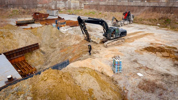 Manzaralı kazıcı ve çekicinin üstünde birlikte eski yük gemisinin yatağının bir kısmını çekiyorlar, mavna, nehir kıyısı, kazma, sökme gemisi, paslı metali kesme, geri dönüşüm....