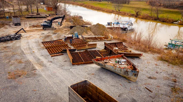 Manzaralı kazıcı ve çekicinin üstünde birlikte eski yük gemisinin yatağının bir kısmını çekiyorlar, mavna, nehir kıyısı, kazma, sökme gemisi, paslı metali kesme, geri dönüşüm....
