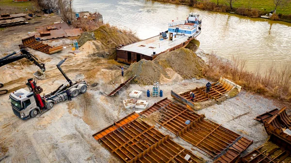 Manzaralı kazıcı ve çekicinin üstünde birlikte eski yük gemisinin yatağının bir kısmını çekiyorlar, mavna, nehir kıyısı, kazma, sökme gemisi, paslı metali kesme, geri dönüşüm....