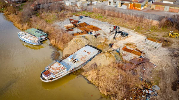 Manzaralı kazıcı ve çekicinin üstünde birlikte eski yük gemisinin yatağının bir kısmını çekiyorlar, mavna, nehir kıyısı, kazma, sökme gemisi, paslı metali kesme, geri dönüşüm....