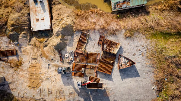 Above view on excavator and tow grapple truck with hydraulic grappling claw, multivalve grab hand, gripper machine, manipulator, loading part of vessel into container, collect rusty metal, recycling.