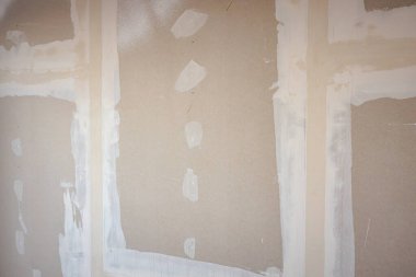 İnşaat alanında inşaat halindeki binanın bölme duvarına kurulmuş kahverengi alçıtaşı tahtalarının ön görüntüsü.