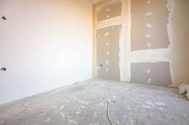 Köşesi, elektrik kabloları ve delikleri olan kahverengi alçıtaşının ön görüntüsü inşaat alanındaki inşaat halindeki binanın bölme duvarına tahtalar monte edilmiş..