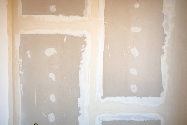 İnşaat alanında inşaat halindeki binanın bölme duvarına kurulmuş kahverengi alçıtaşı tahtalarının ön görüntüsü.