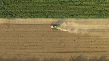 Üst manzarada, doli yukarı doğru hareket ediyor, tarım hasat makinesinin üzerinde dönüyor, tarım arazilerinde olgun buğdayları kesip biçerken birleşiyor. Yaz mevsiminde hasat zamanı. 