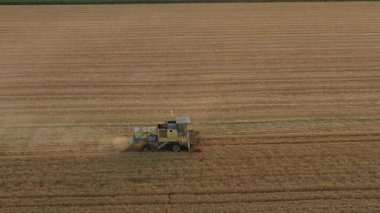 Yukarıda, doli hareket, tarımın yörüngesinde, modası geçmiş, modası geçmiş, eski moda sarı kombine, biçerken biçerdöver, tarım arazilerindeki olgun buğdayları hasat ediyor. Yaz mevsiminde hasat zamanı. 