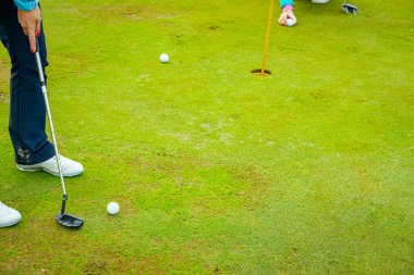 İnsanlar golf oynuyor, golf oynarken çim sahası, saha. Odaklanmış golfçü, topu deliğe, konsantrasyona ve hassasiyete sokmayı hedefleyen pitoresk bir golf sahası..