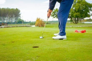 İnsanlar golf oynuyor, golf oynarken çim sahası, saha. Odaklanmış golfçü, topu deliğe, konsantrasyona ve hassasiyete sokmayı hedefleyen pitoresk bir golf sahası..