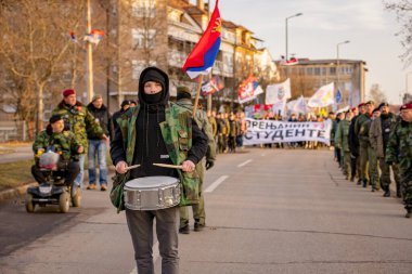Zrenjanin, Sırbistan - 25 Ocak 2026: Öğrencilerin hükümet yolsuzluğu ve rejimine karşı düzenlediği protestoda bereli bir grup savaş gazisi, trajik bir kazada hayatını kaybeden 16 kişi için adalet talep ediyor