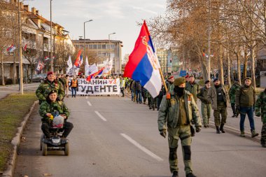 Zrenjanin, Sırbistan - 25 Ocak 2026: Öğrencilerin hükümet yolsuzluğu ve rejimine karşı düzenlediği protestoda bereli bir grup savaş gazisi, trajik bir kazada hayatını kaybeden 16 kişi için adalet talep ediyor