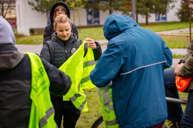 Zrenjanin, Voyvodina, Sırbistan - 29 Kasım 2025: Yağmurlu bir günde şehirde bisiklet sürmek için toplanan bir grup insan, şehir trafiğindeki bisikletçilerin tehlikesine dikkat çekmek için düdük kullanıyor.