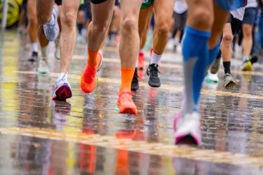 Ayakları ve bacakları düşük, büyük bir grup koşucu, atletler sokak maratonu yarışması, yağmurlu bir günde yarışan insan kalabalığı.