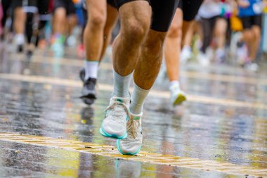 Ayakları ve bacakları düşük, büyük bir grup koşucu, atletler sokak maratonu yarışması, yağmurlu bir günde yarışan insan kalabalığı.