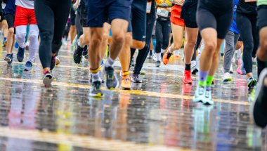 Ayakları ve bacakları düşük, büyük bir grup koşucu, atletler sokak maratonu yarışması, yağmurlu bir günde yarışan insan kalabalığı.