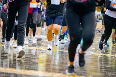 Ayakları ve bacakları düşük, büyük bir grup koşucu, atletler sokak maratonu yarışması, yağmurlu bir günde yarışan insan kalabalığı.
