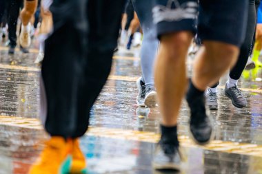 Ayakları ve bacakları düşük, büyük bir grup koşucu, atletler sokak maratonu yarışması, yağmurlu bir günde yarışan insan kalabalığı.