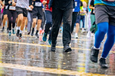 Ayakları ve bacakları düşük, büyük bir grup koşucu, atletler sokak maratonu yarışması, yağmurlu bir günde yarışan insan kalabalığı.