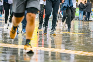 Ayakları ve bacakları düşük, büyük bir grup koşucu, atletler sokak maratonu yarışması, yağmurlu bir günde yarışan insan kalabalığı.