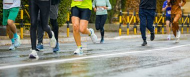 Ayakları ve bacakları düşük, büyük bir grup koşucu, atletler sokak maratonu yarışması, yağmurlu bir günde yarışan insan kalabalığı.