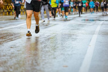 Ayakları ve bacakları düşük, büyük bir grup koşucu, atletler sokak maratonu yarışması, yağmurlu bir günde yarışan insan kalabalığı.