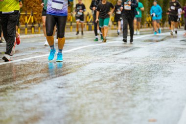 Ayakları ve bacakları düşük, büyük bir grup koşucu, atletler sokak maratonu yarışması, yağmurlu bir günde yarışan insan kalabalığı.